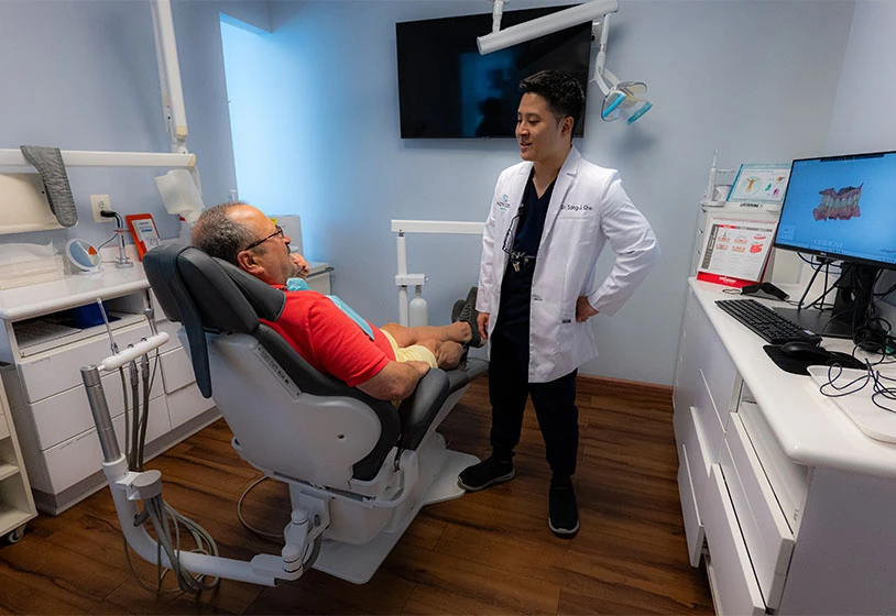 Dr. Cho explaining restorative dentistry to male patient with red shirt and glasses